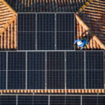 aerial view of Two workers installing solar panels on a house roof