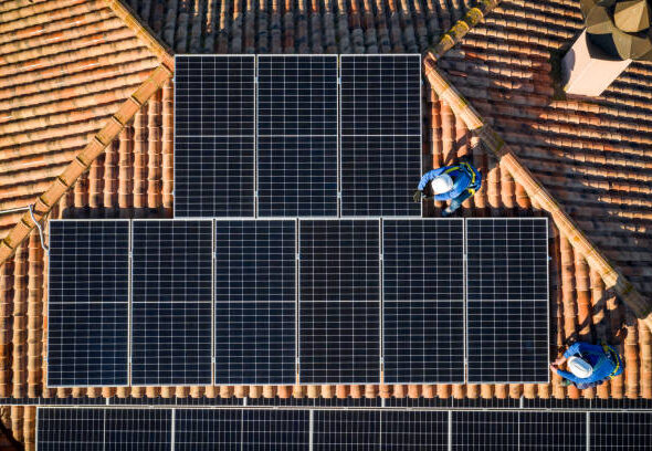 aerial view of Two workers installing solar panels on a house roof